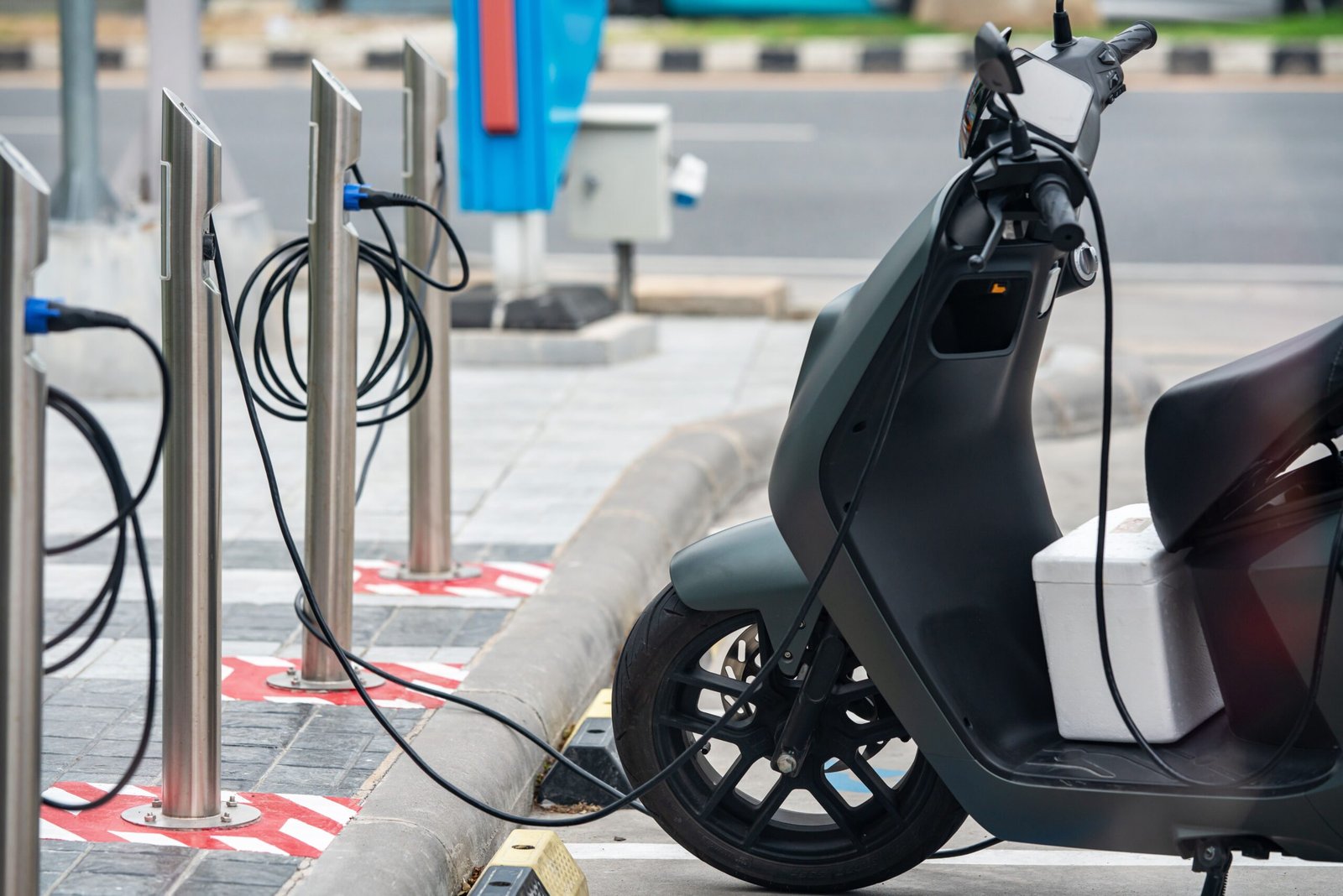 Electric scooter plugged into a charging station in a city environment, showcasing eco-friendly urban transportation.